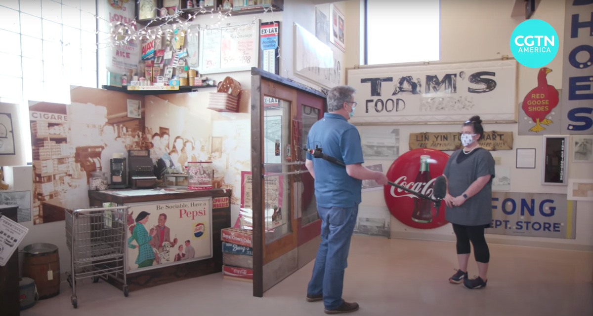 Curator of Mississippi Delta Chinese Heritage Museum interviewed amidst signage and photographs of businesses owned by Chinese families