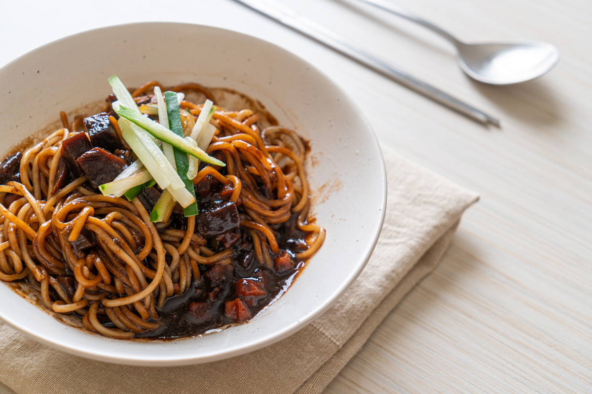 Bowl of Korean Jajangmyeon noodles with black sauce topped with cucumber