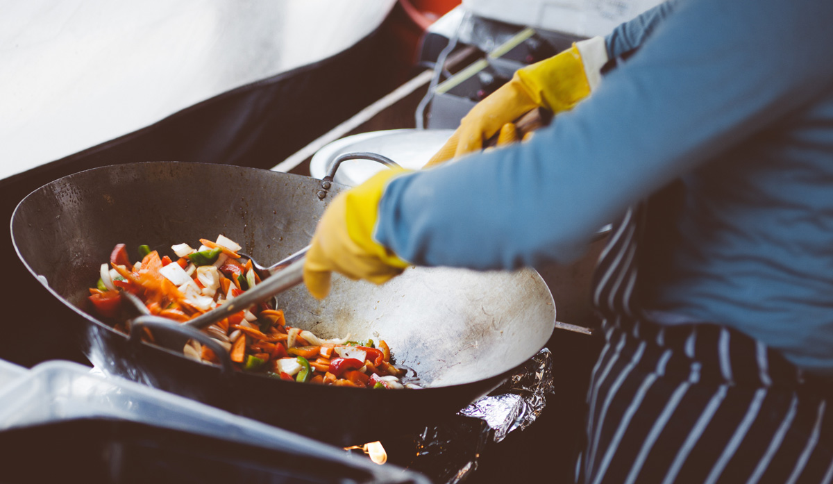 Person stir-frying vegetables in a wok
