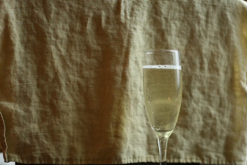 A 3/4 full glass of sparkling wine.