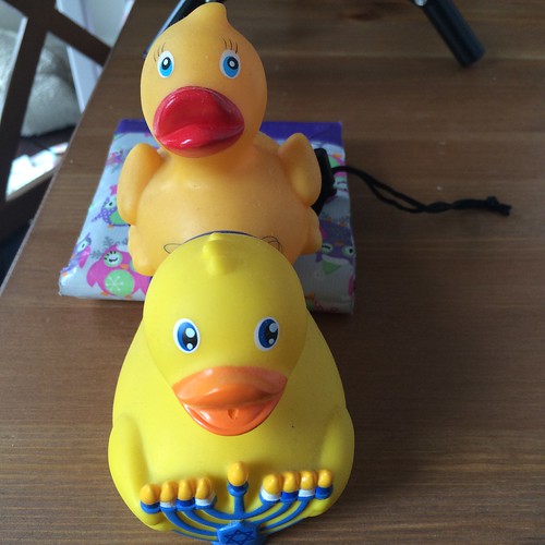 Two rubber duckys on top of each other, one supported by a wallet.