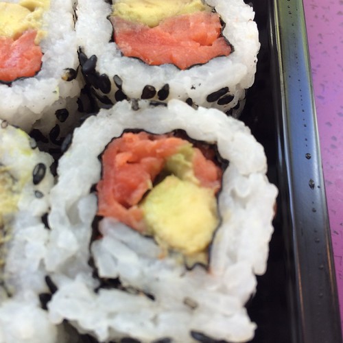 A very close-up shot of a slice of sushi roll containing smoked salmon and avocado.