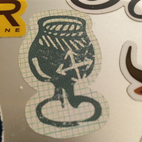 A very close up shot of a sticker; it's a stylized tuilp glass with the Crux Brewing logo on it.